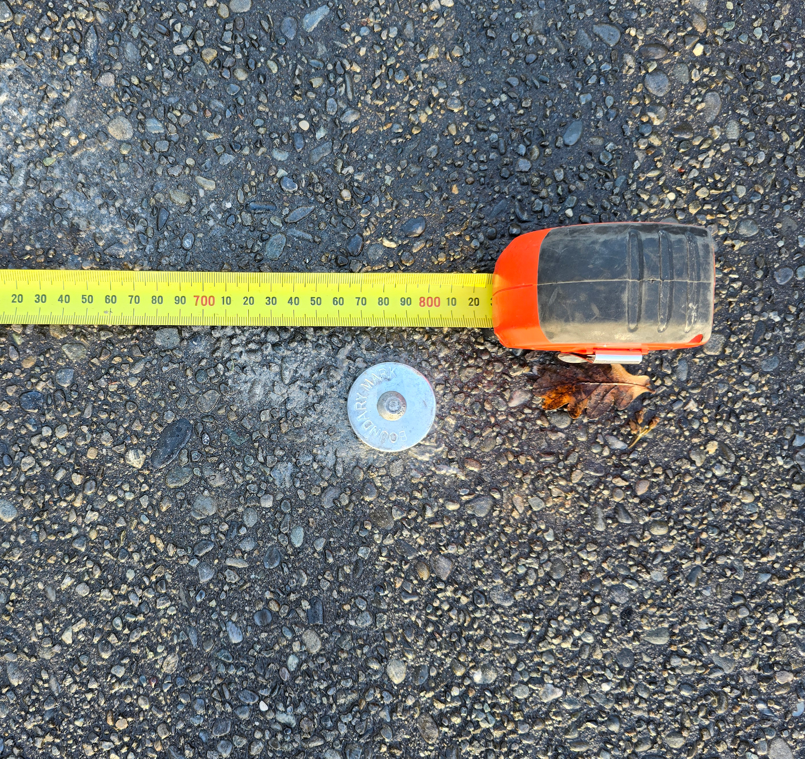 A metal boundary marker in a residential driveway in New Zealand.