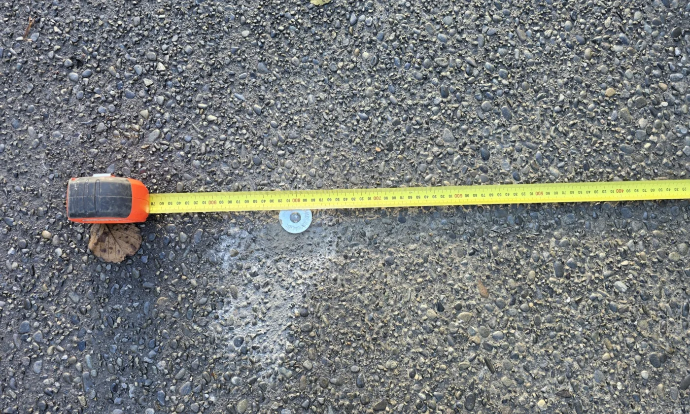 A metal boundary marker placed in a driveway in New Zealand.