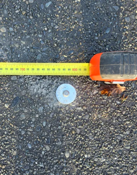 A metal boundary marker in a residential driveway in New Zealand.